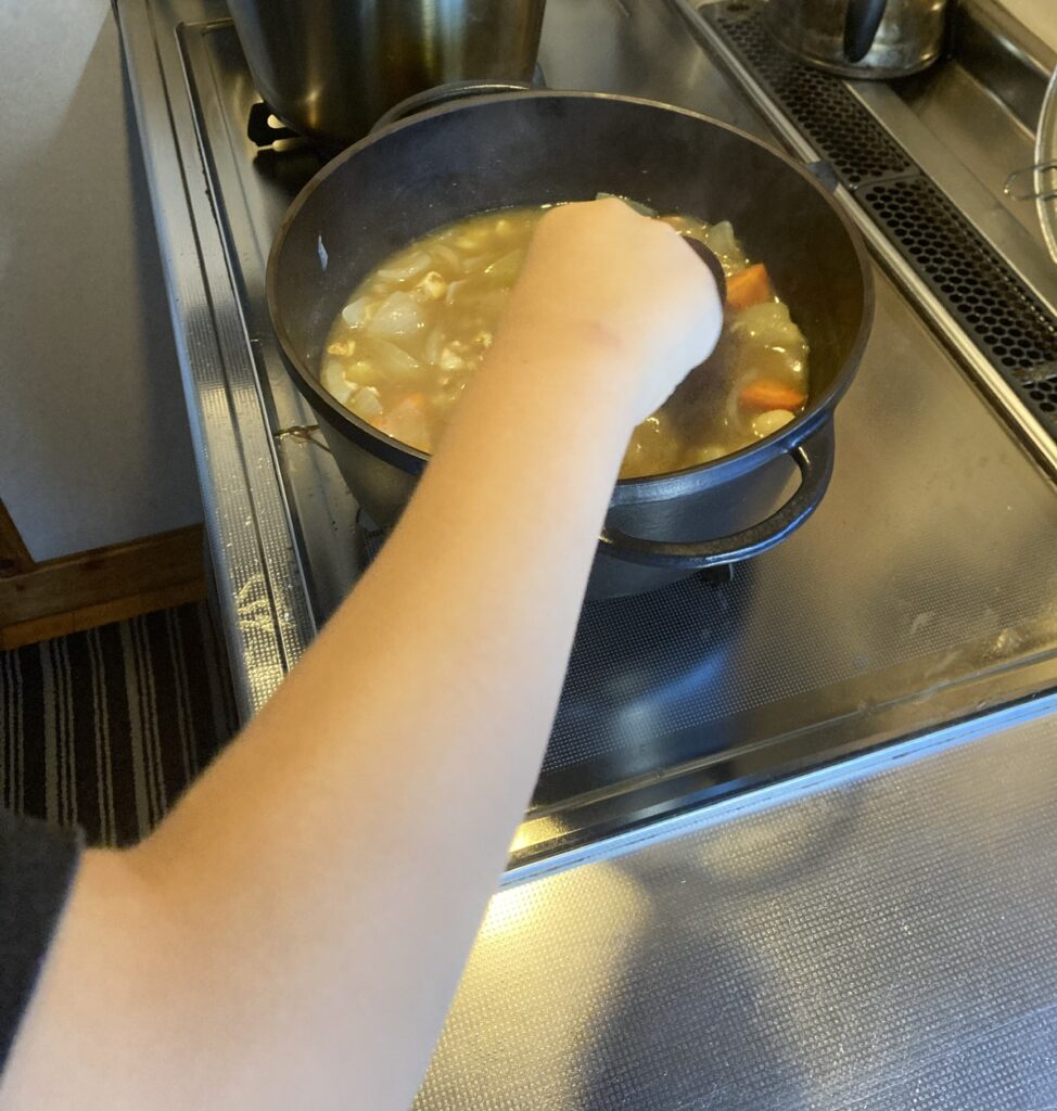 カレールーを入れて鍋をかき混ぜる長男